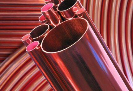 A straight length copper pipe on a background of many copper pipes aligned in a uniform way.